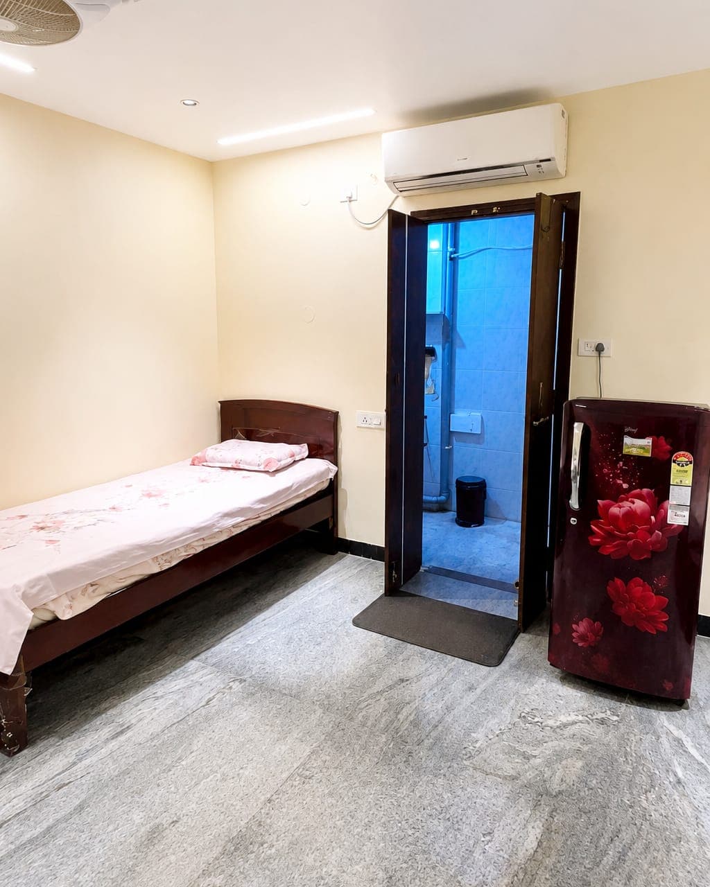 A furnished room with attached bathroom and fridge